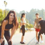 role of exercise in mental health - Young sporty girl smiles on the background of friends athletes in the park. Health. Healthy lifestyle.