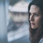 Young woman looking through window with reflection