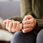 Close-up of a person nervously fidgeting with their hands and sweater sleeve, suggesting anxiety, stress, or emotional discomfort.